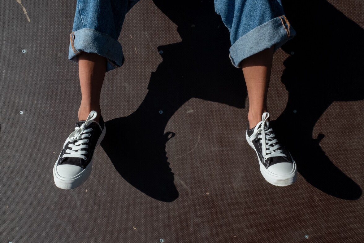 Close up shot of feet hanging with chuck style shoes on.  Custom foot orthotics can be very helpful in this style of footwear in Toronto.