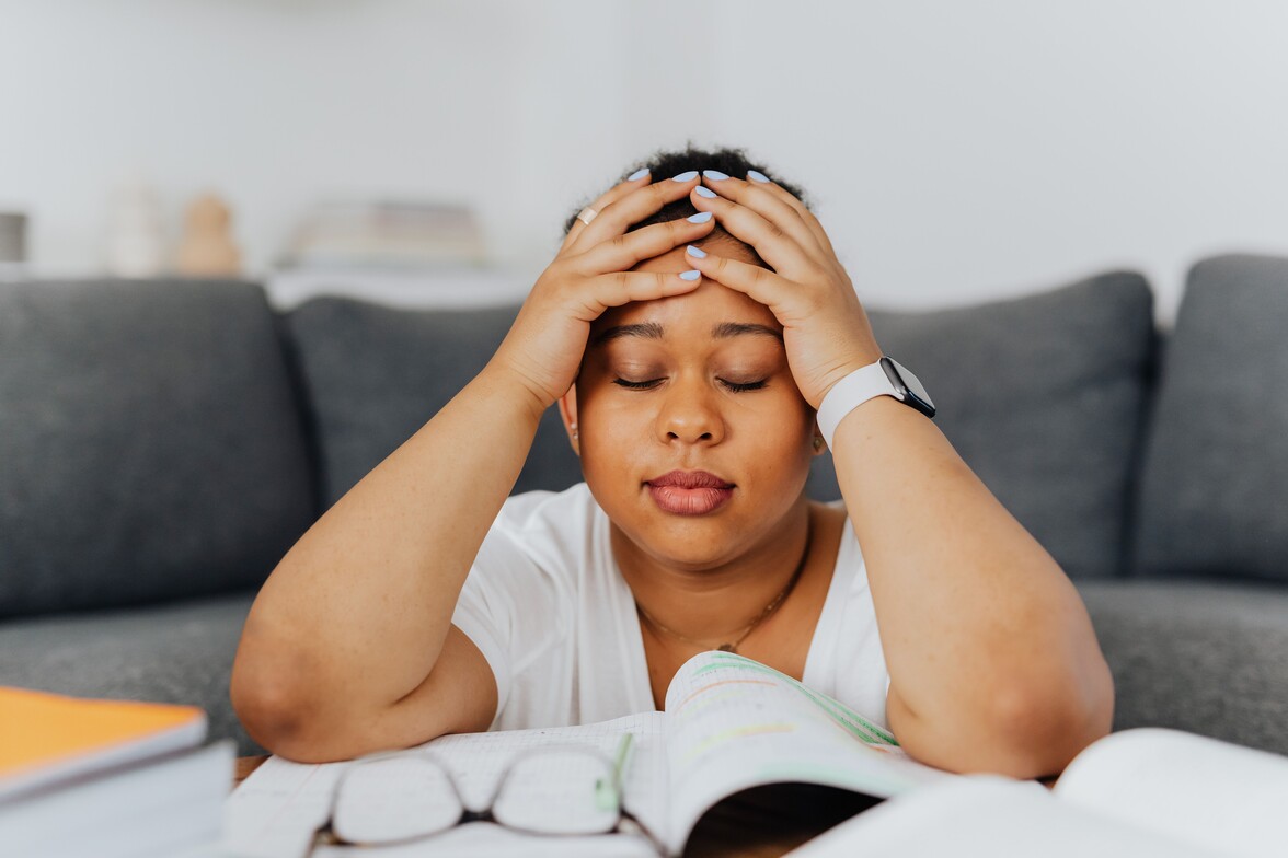 A woman holding her head with her eyes closed because she is stressed.